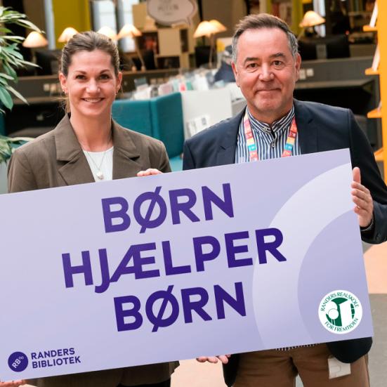 Gitte og Jens med skiltet hvor der står: Børn hjælper Børn