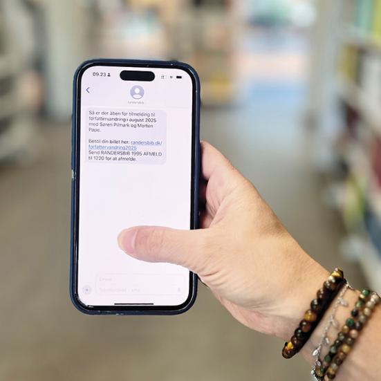 Hånd der holder en mobiltelefon med en sms på skærmen