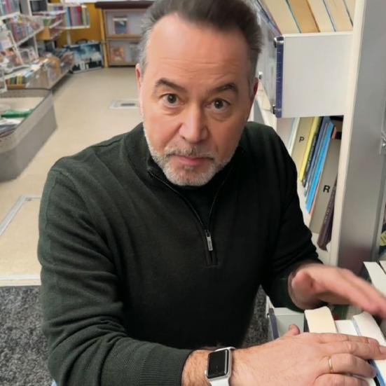 Jens Sørensen sidder i Bogbussen og kigger i en bogreol