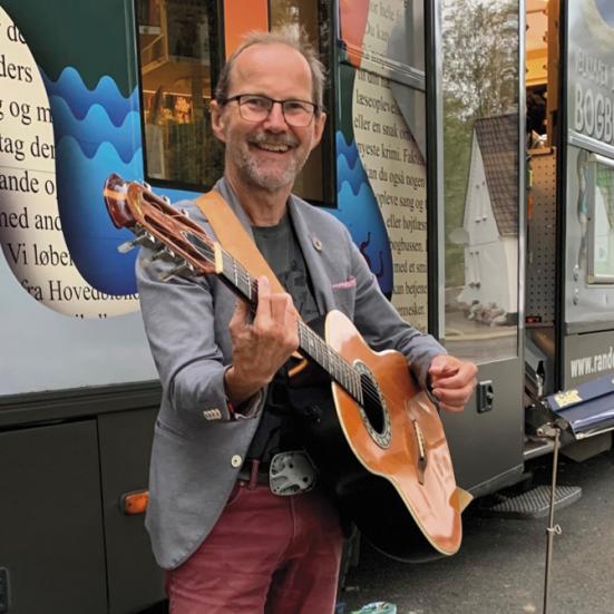 Peter Elmelund med en guitar foran Bogbussen