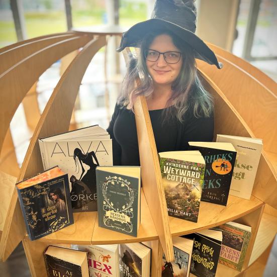 Heks på biblioteket sammen med udvalgte bøger om hekse