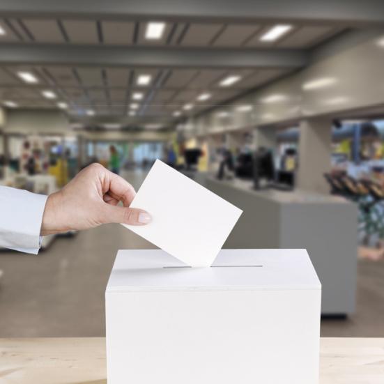 En hånd kommer en stemmeseddel i en stemmeurne