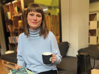 Cissel Enemark læser med en kop kaffe i hånden