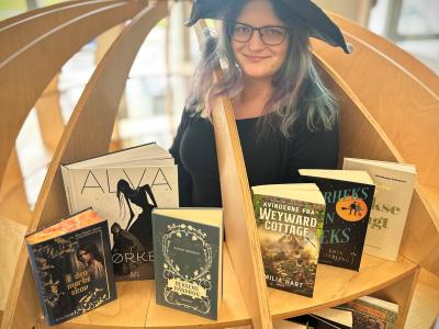 Heks på biblioteket sammen med udvalgte bøger om hekse