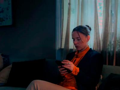 Kvinde med mobiltelefon i en mørk stue