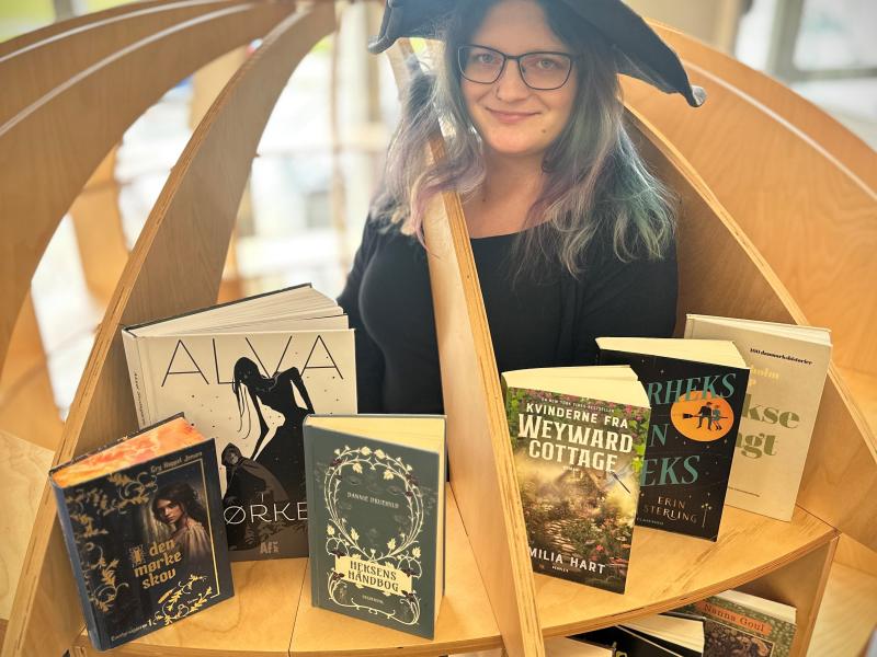 Heks på biblioteket sammen med udvalgte bøger om hekse