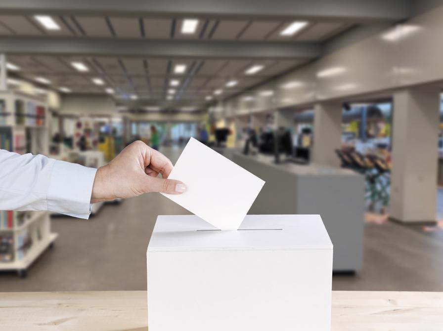 En hånd kommer en stemmeseddel i en stemmeurne